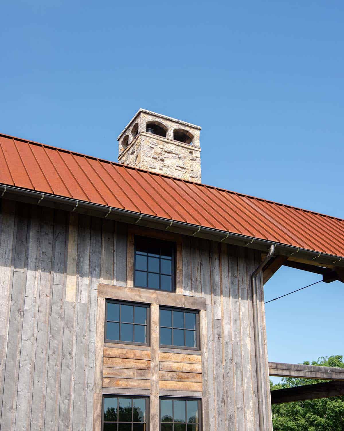 Stone chimney with arched caps above rusted standing-seam roof