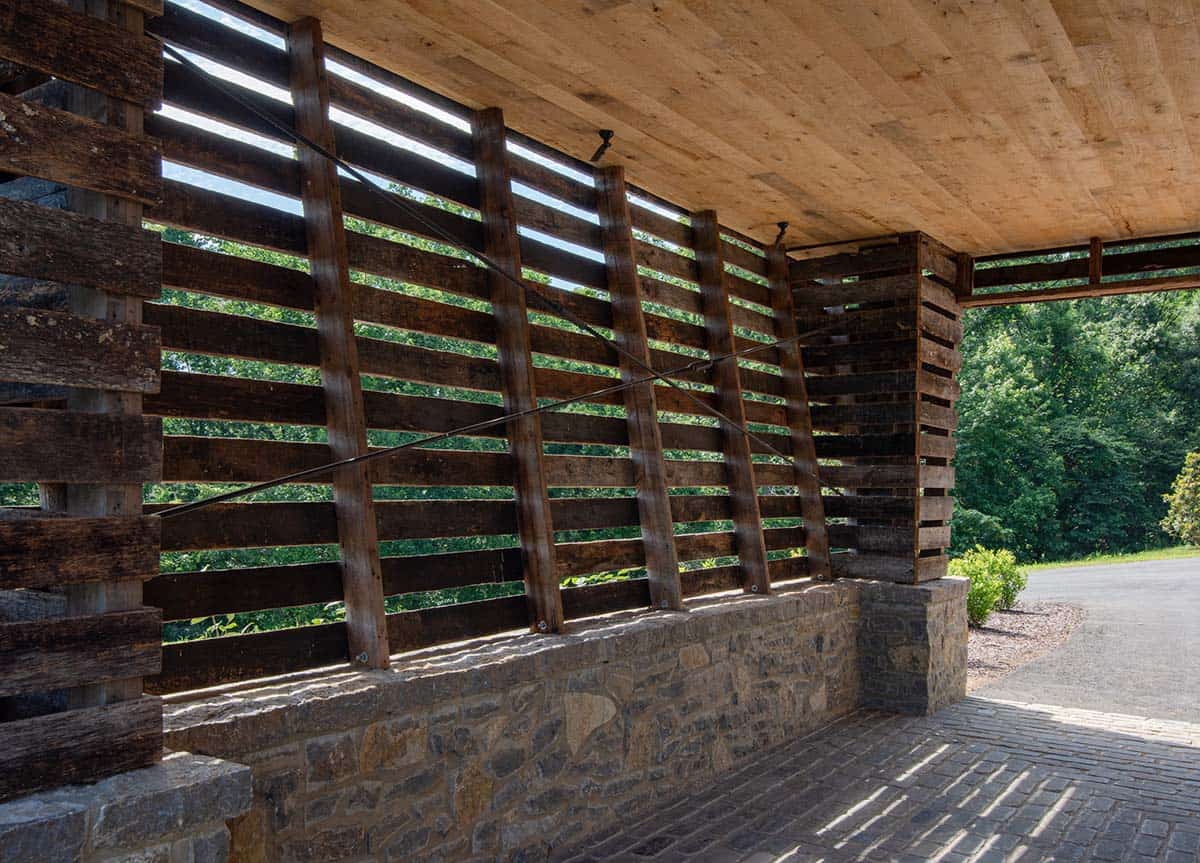 Slatted reclaimed wood wall on stone base inside covered entry