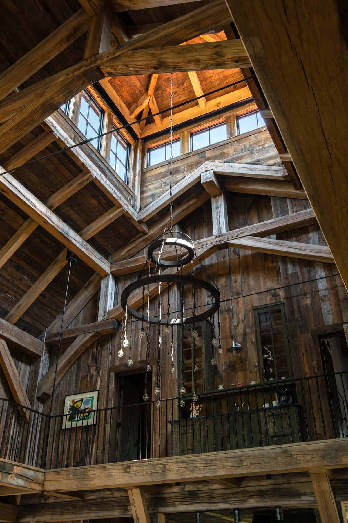 Ring chandelier hanging beneath cupola in timber-frame ceiling