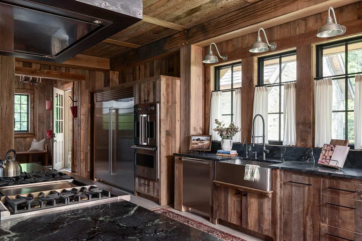 Hammered farmhouse sink below gooseneck sconces and cafe curtains