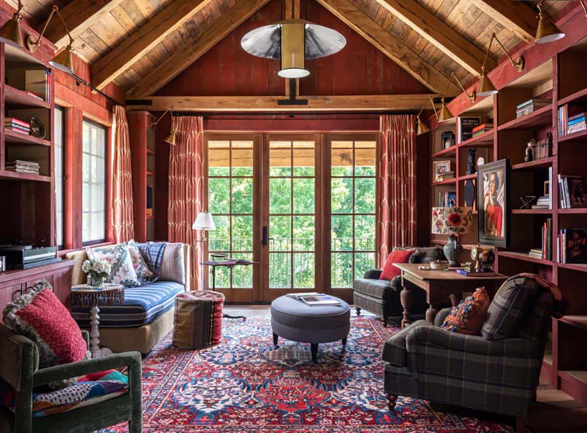 Red-painted library with built-in bookshelves and brass sconces