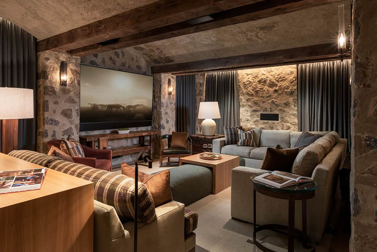 Media room with plaid sofa and gray sectional under timber beams