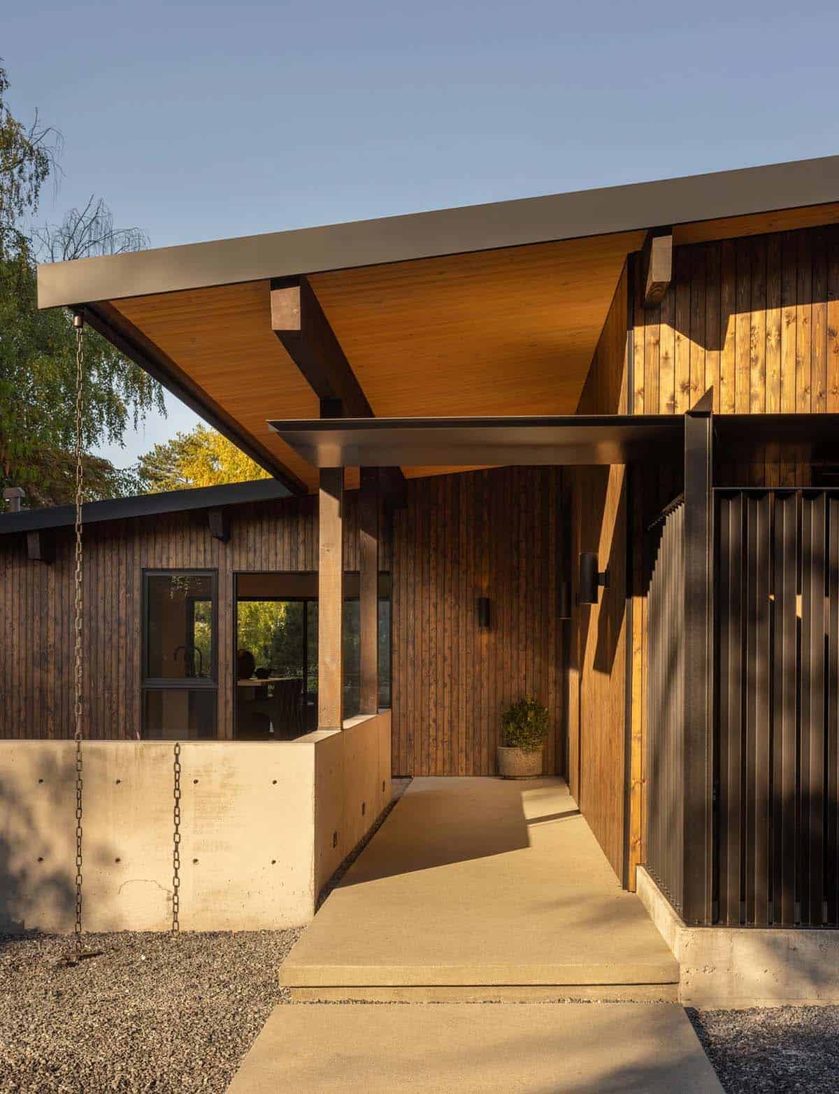 Covered entry walk with concrete wall, rain chain, and stained cedar siding