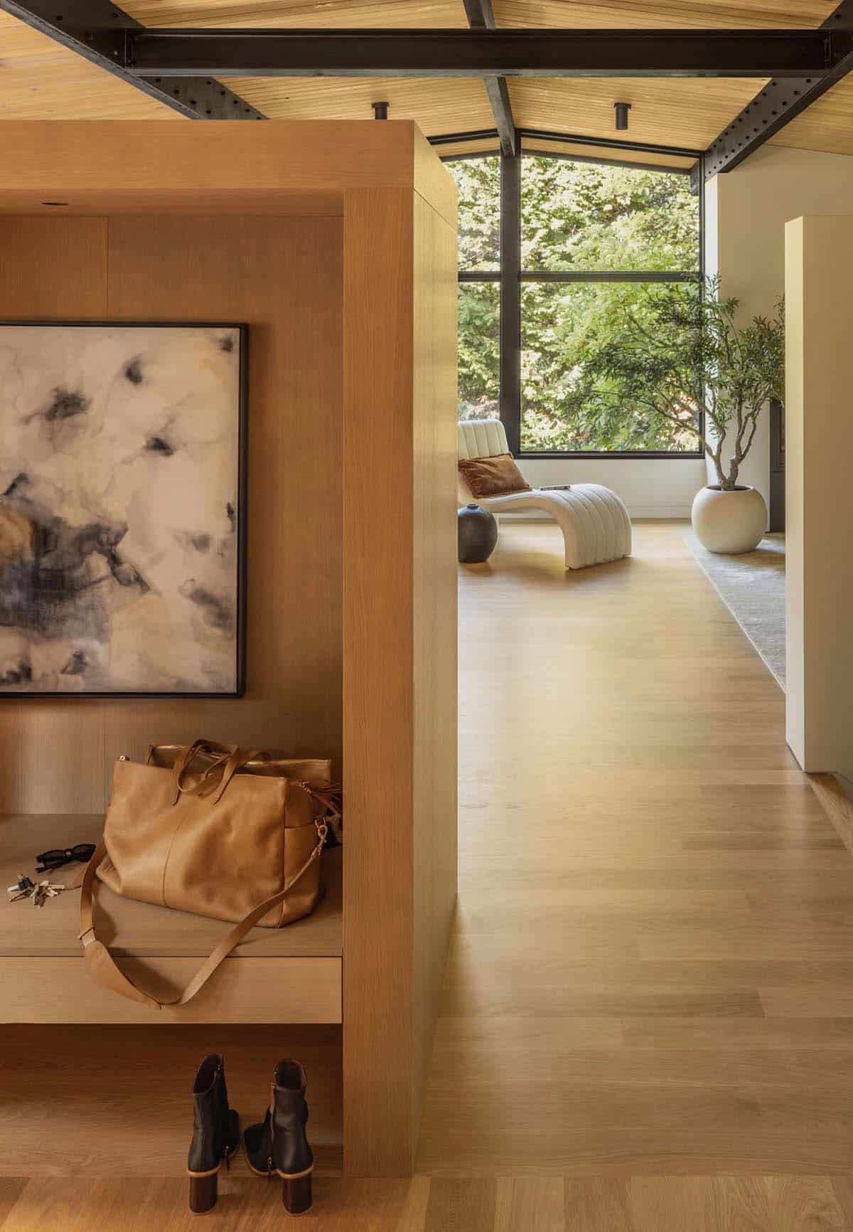 White oak entry bench with abstract painting, opening to sitting area with corner windows