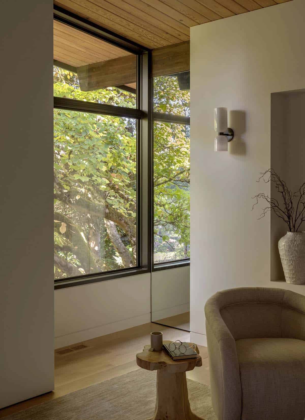 Reading corner with swivel chair, teak stool, and corner window to trees