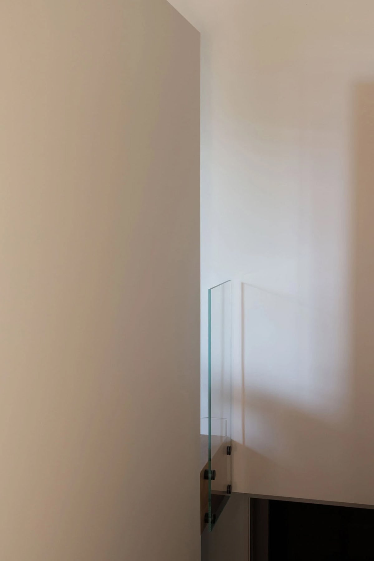 Glass partition at end of white wall above stairwell