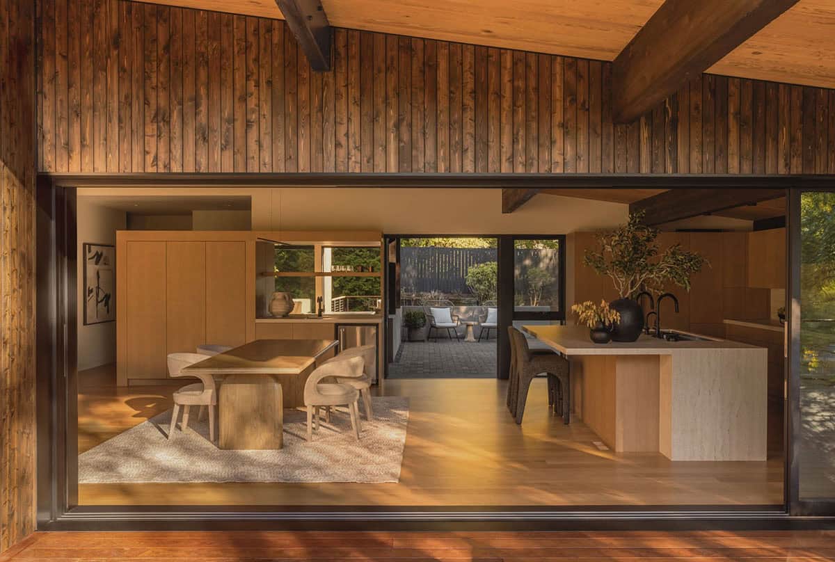 View from deck through open glass wall to dining area and kitchen island