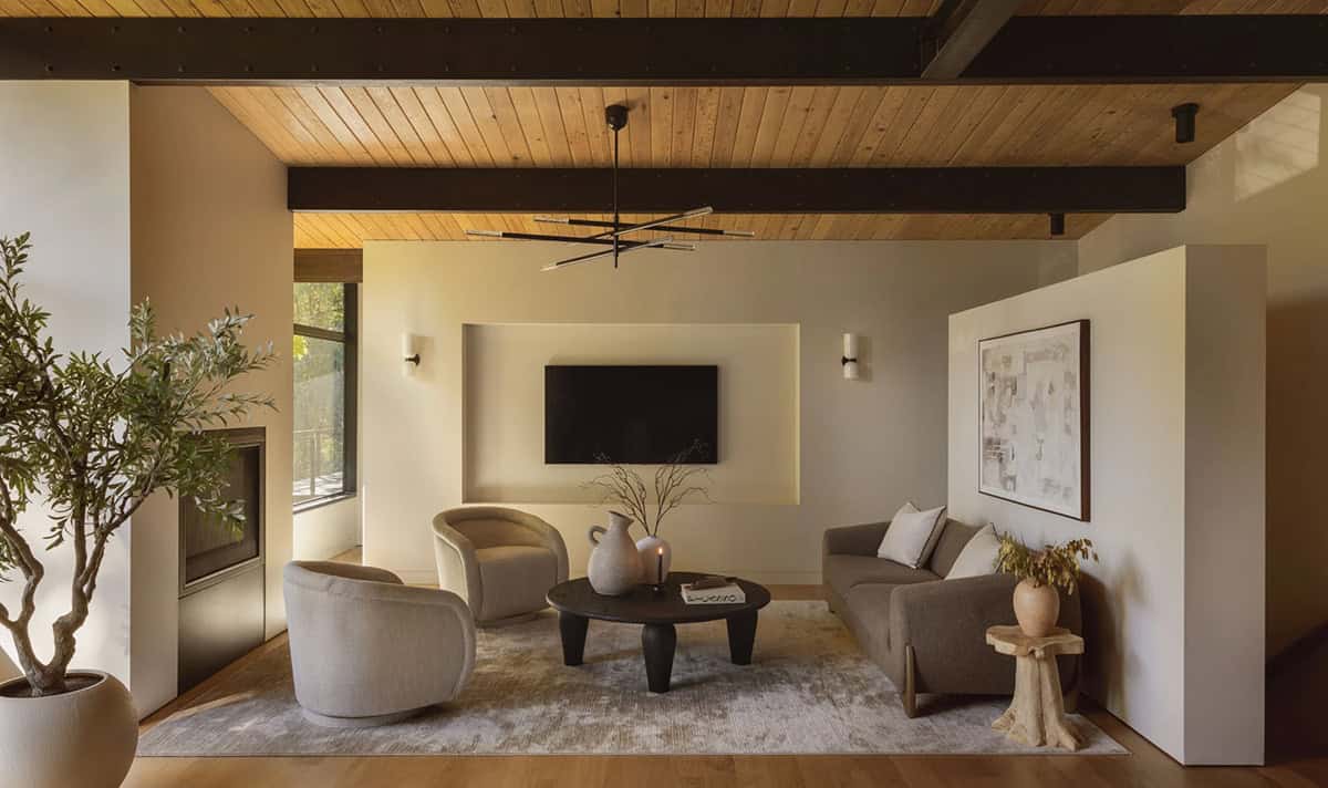 Living room with swivel chairs, round black coffee table, and steel-reinforced ceiling beams