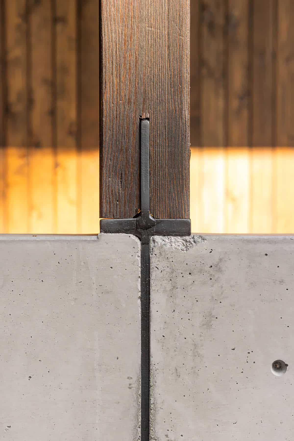 Timber post set on concrete wall with black steel connector