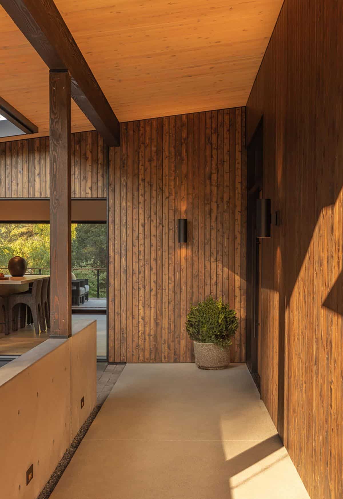 Covered breezeway entry with concrete wall, timber post, and view to kitchen