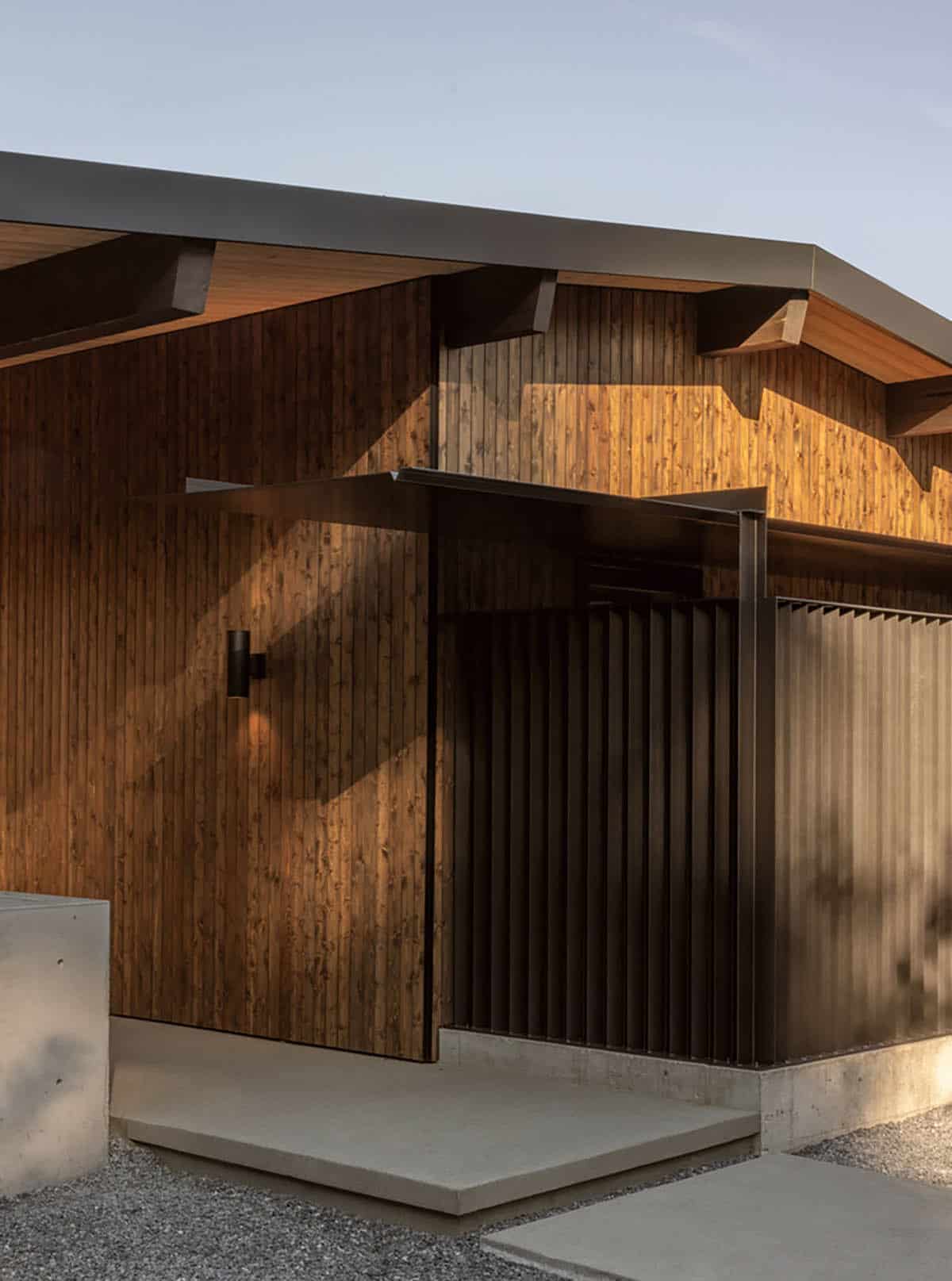 Entry corner with steel slat screen, cedar siding, and steel-covered walkway