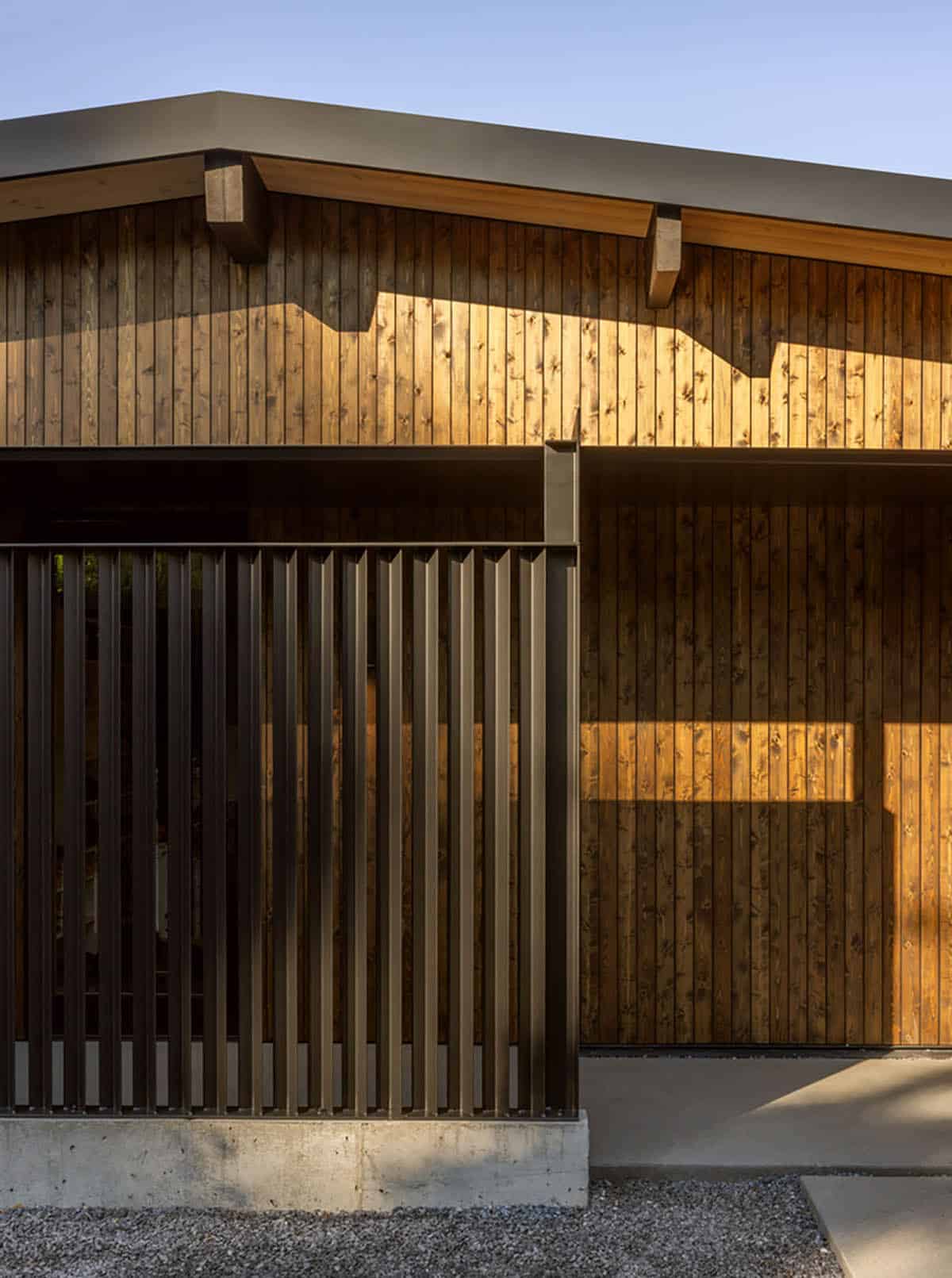 Black steel slat screen on concrete base in front of cedar siding