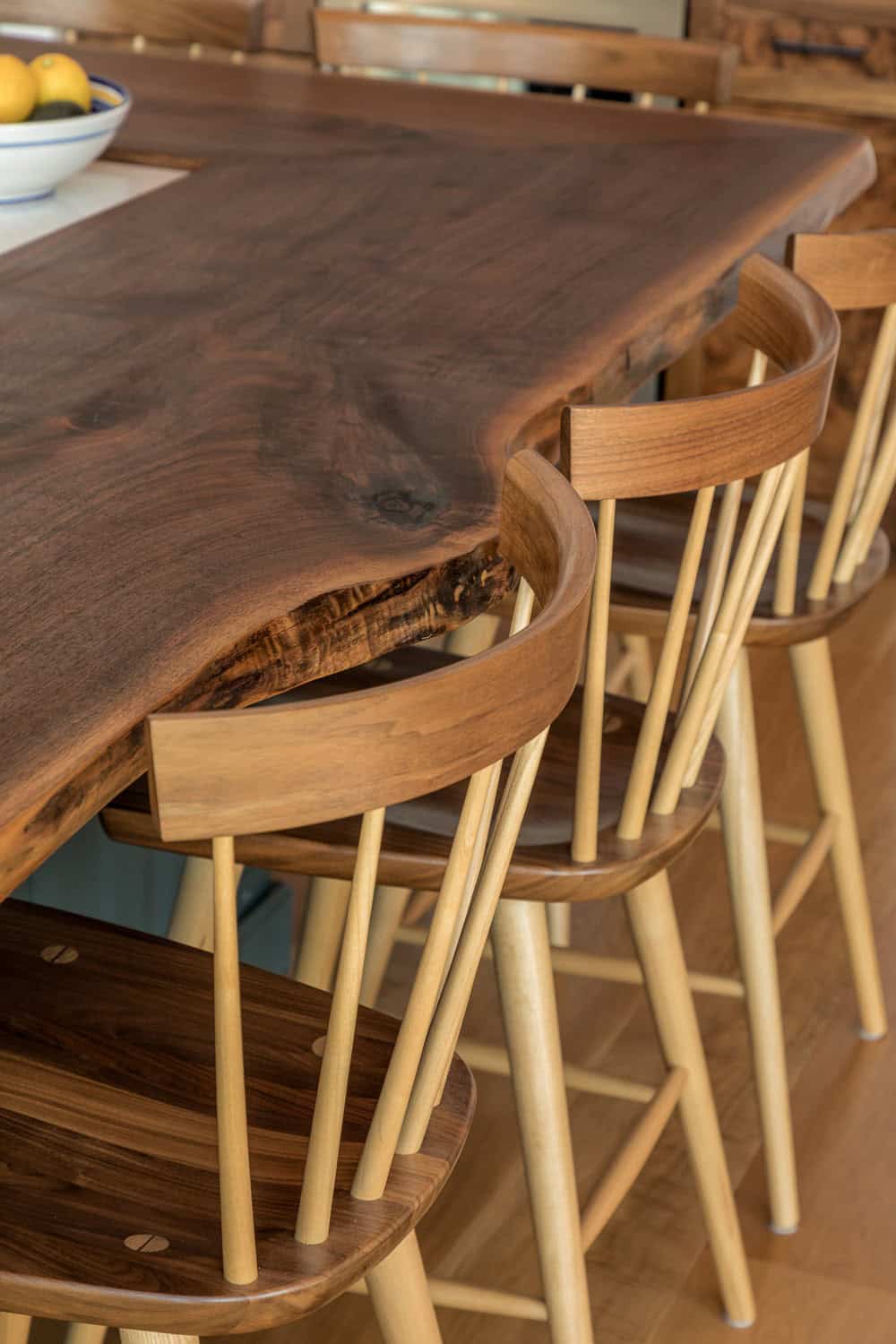Close-up of a live-edge wood island counter and spindle-back bar stools