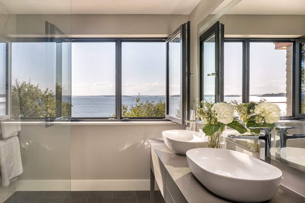 Bathroom with two vessel sinks and open windows overlooking the bay