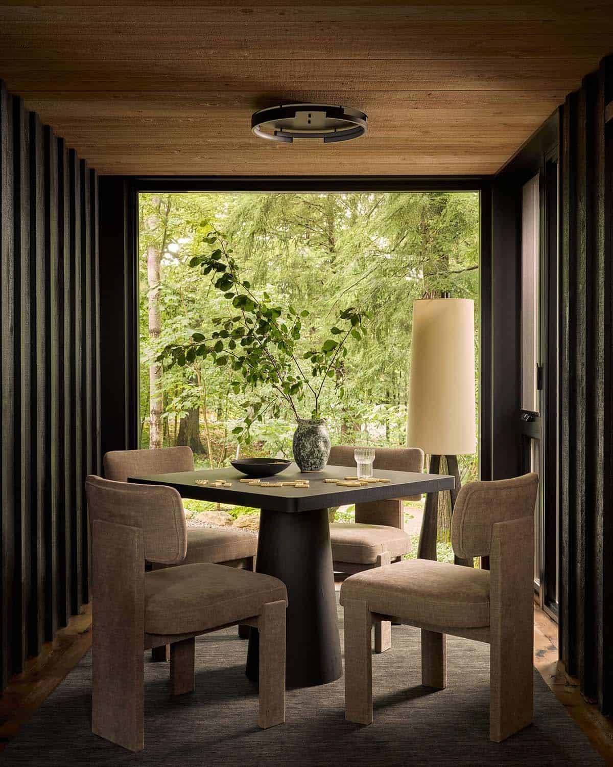 Game table with upholstered chairs facing a picture window