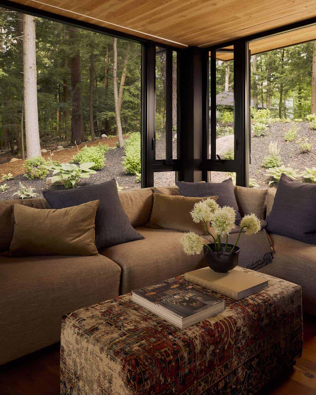 Corner sectional with vintage rug ottoman and forest views