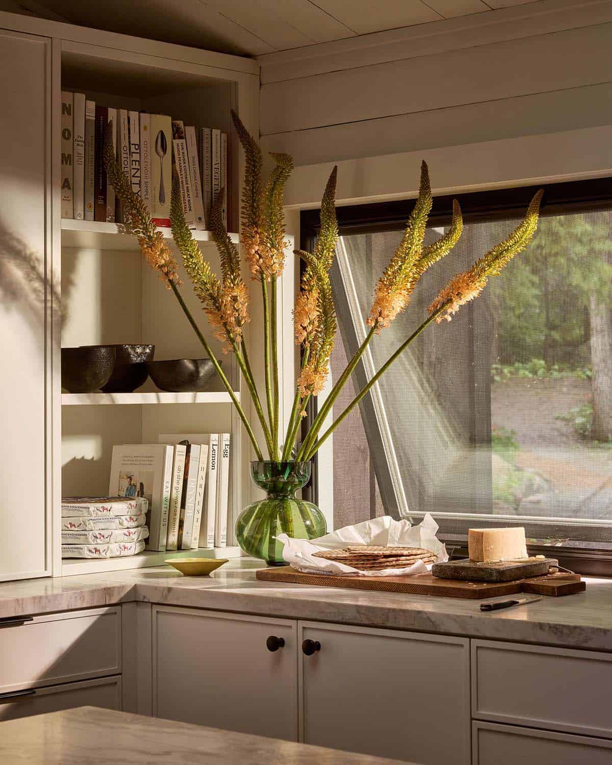 Kitchen shelves with cookbooks and foxtail lilies by the window