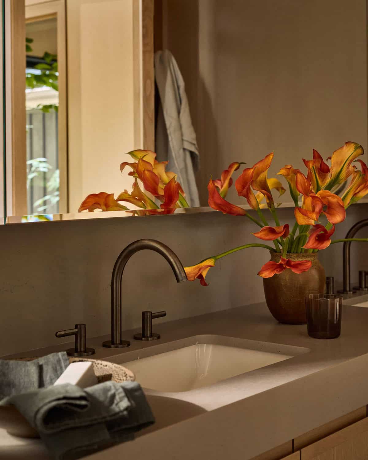 Bathroom vanity with bronze faucet and orange calla lilies