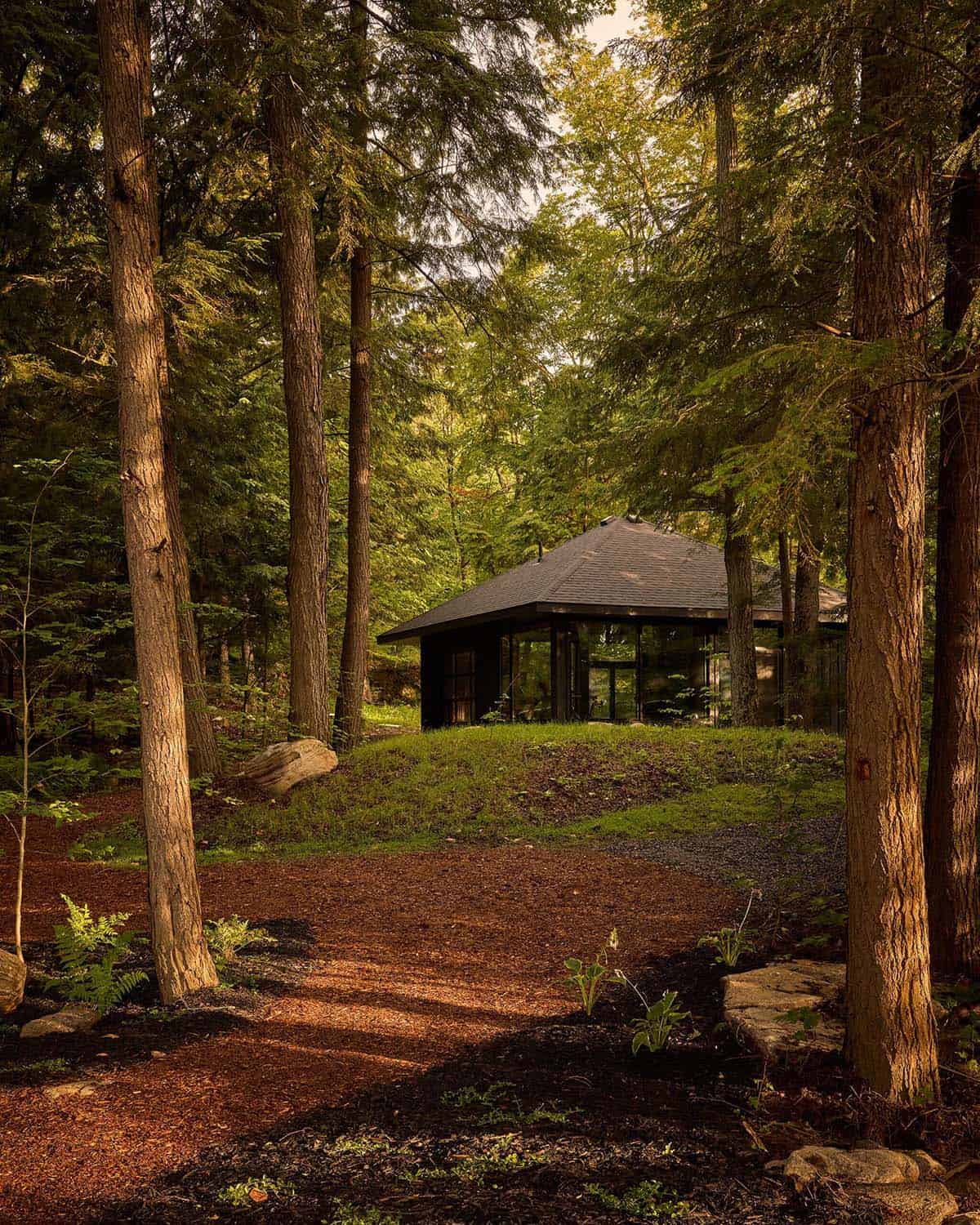 Hip-roof pavilion on a grassy rise among tall trees