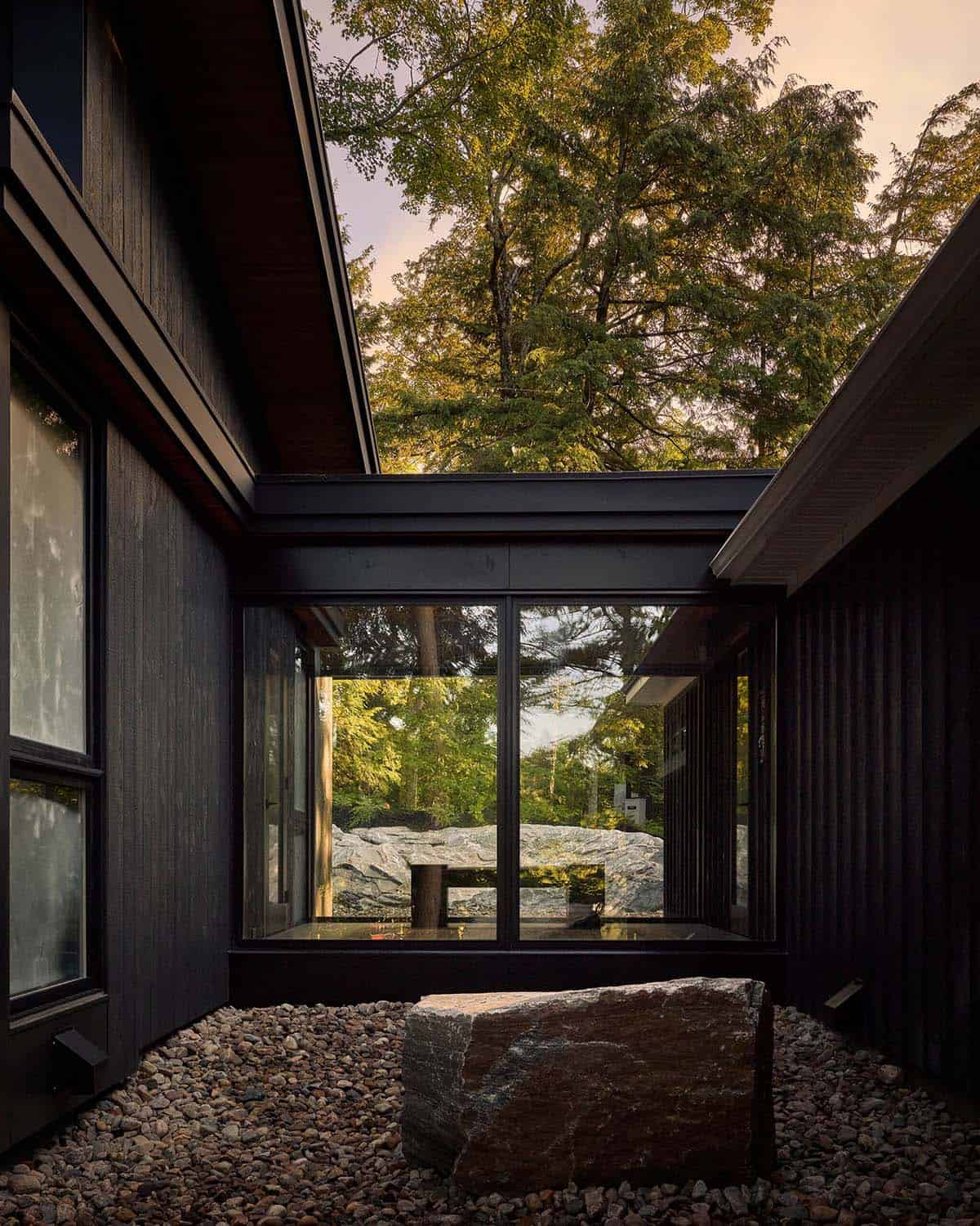 Courtyard boulder framed by charred wood walls and glass