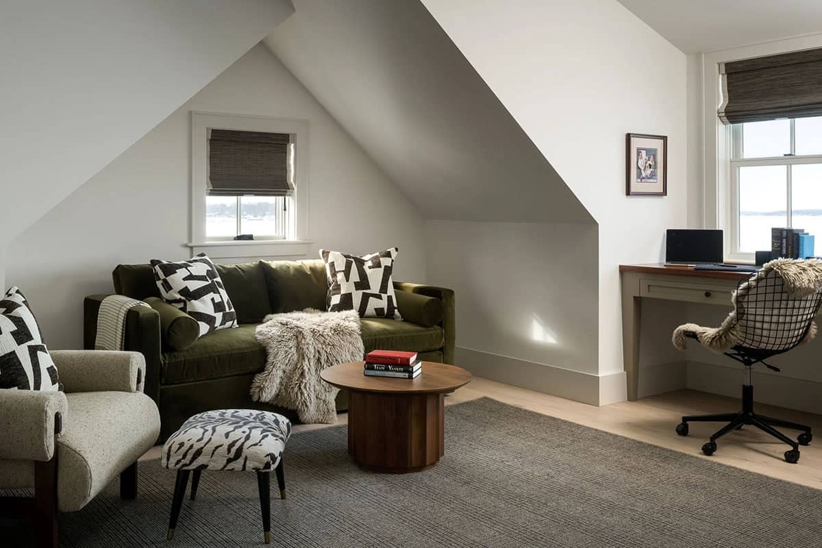 Upstairs sitting room with green velvet sofa, walnut drum coffee table, built-in desk, and lake views