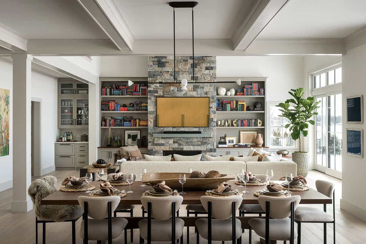 Dining and living area with walnut table, stone fireplace wall with built-in bookshelves, and coffered ceiling