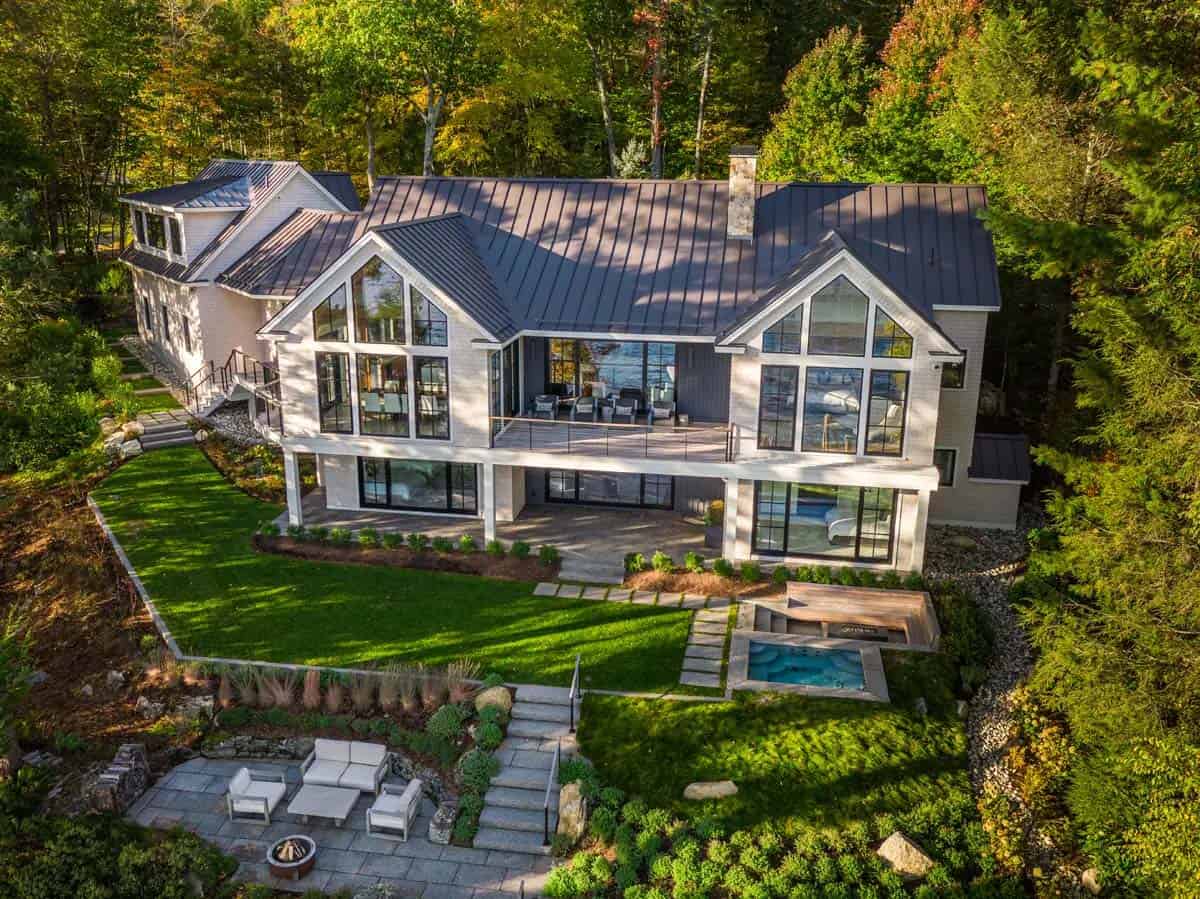 Elevated view of the lake house with lawn, hot tub, and lakeside seating area
