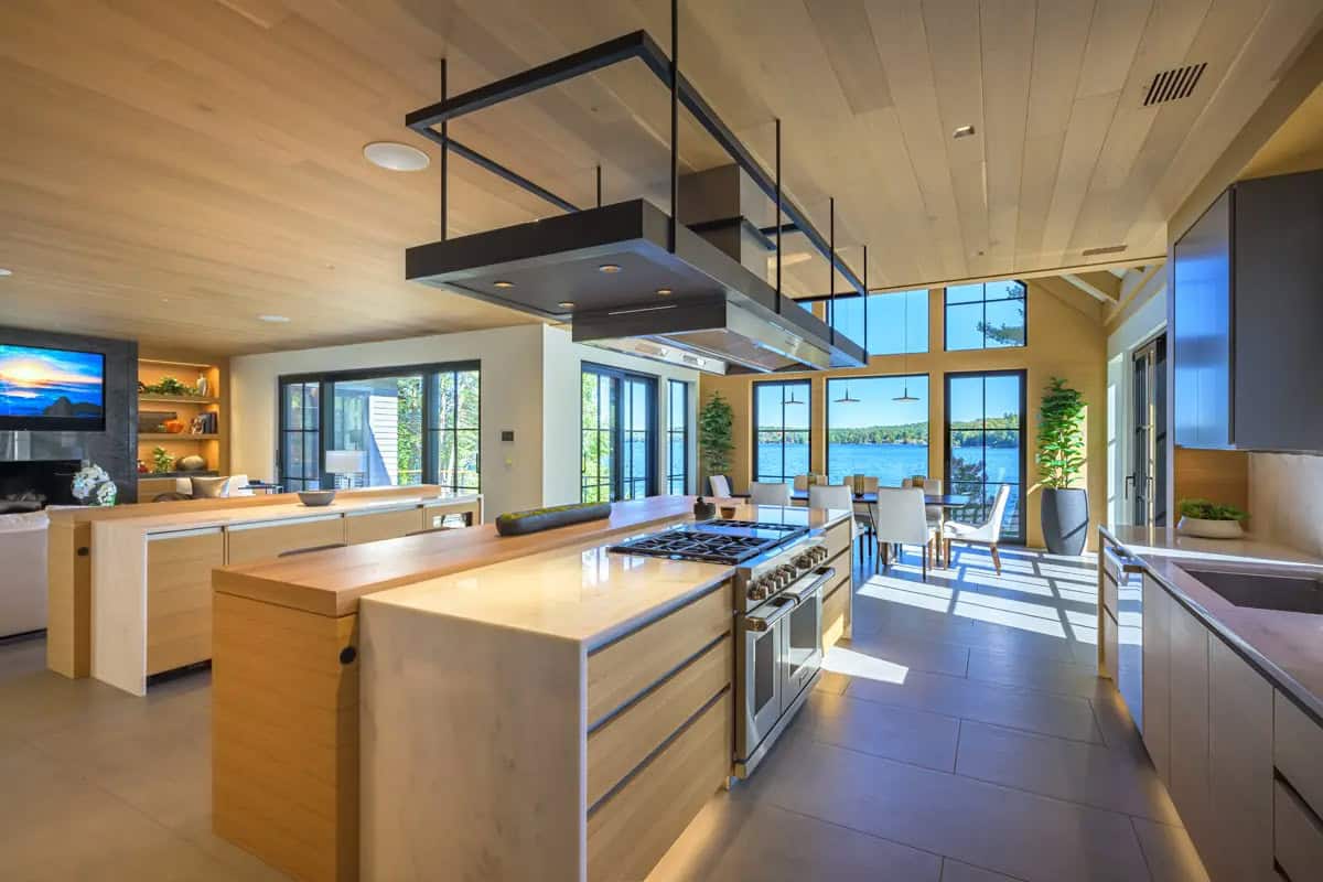 Kitchen island with a waterfall countertop and range, opening to the dining room and living area