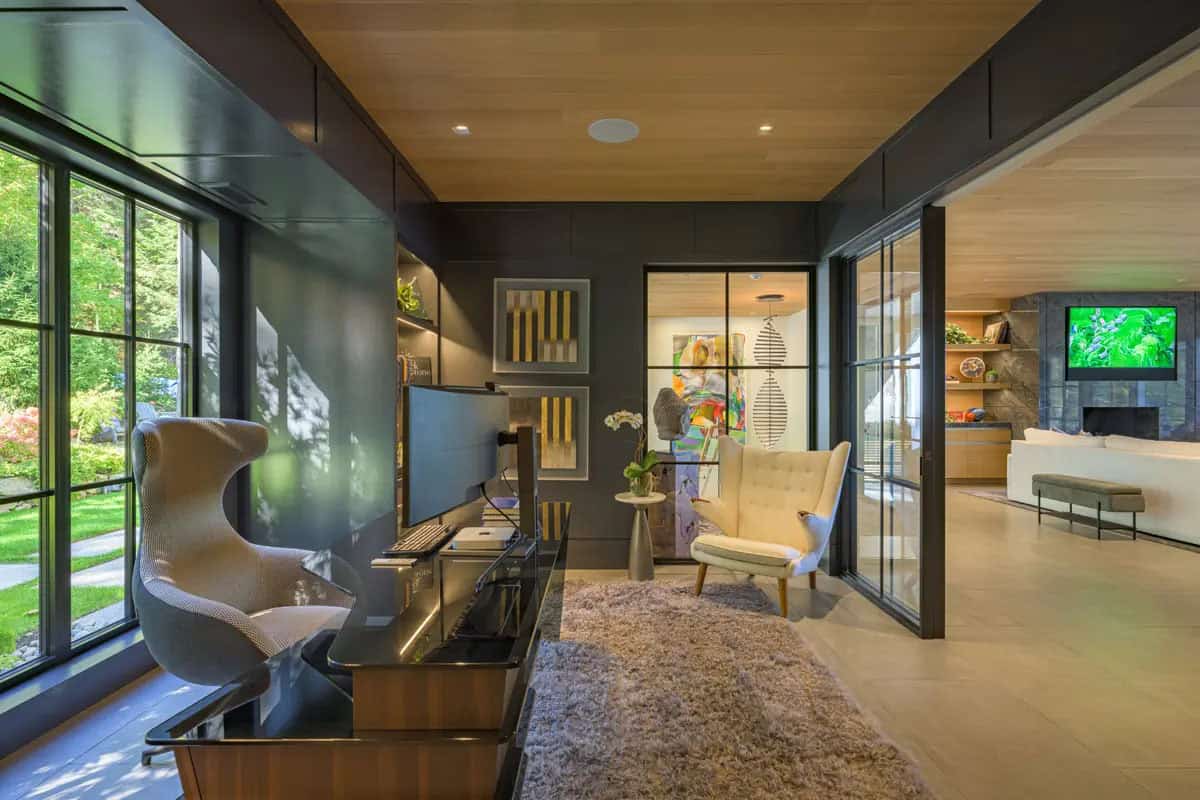 Office and den with black steel-framed glass walls opening to the living room