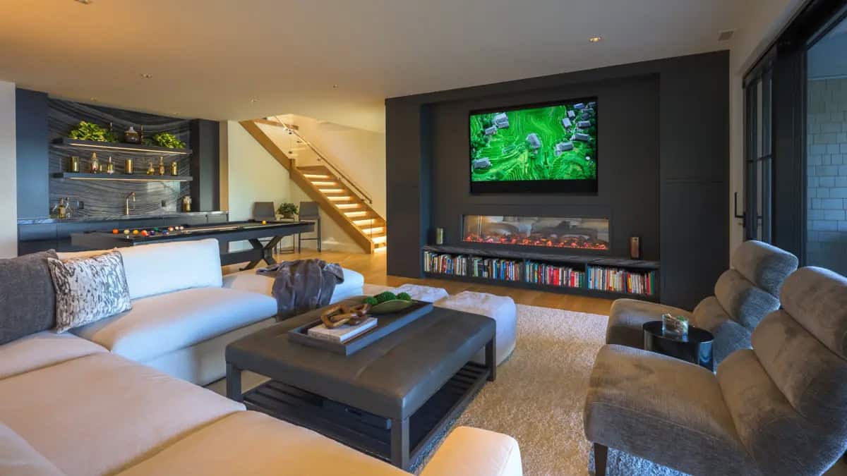 Lower-level family room with a linear fireplace, a pool table, a wet bar, and an illuminated staircase