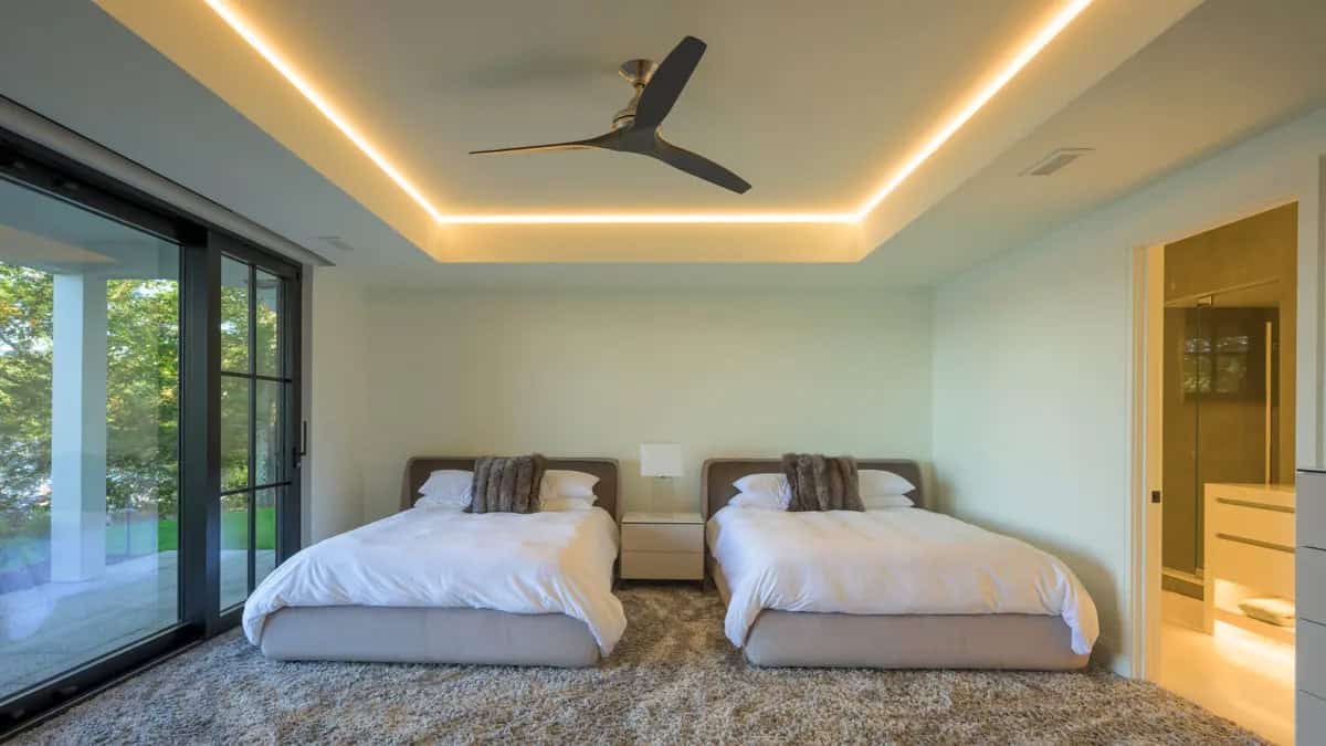 Guest bedroom with twin beds, a glowing cove-lit ceiling, and sliding glass doors to the patio