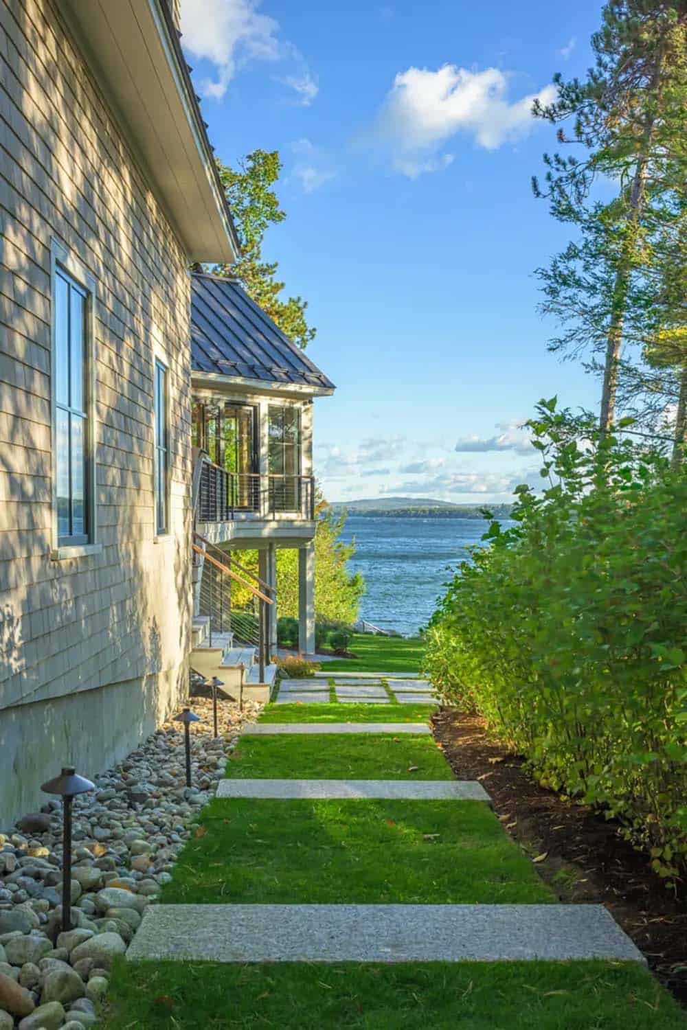 Grass and stone-slab path along the shingled side of the house, leading toward the lake