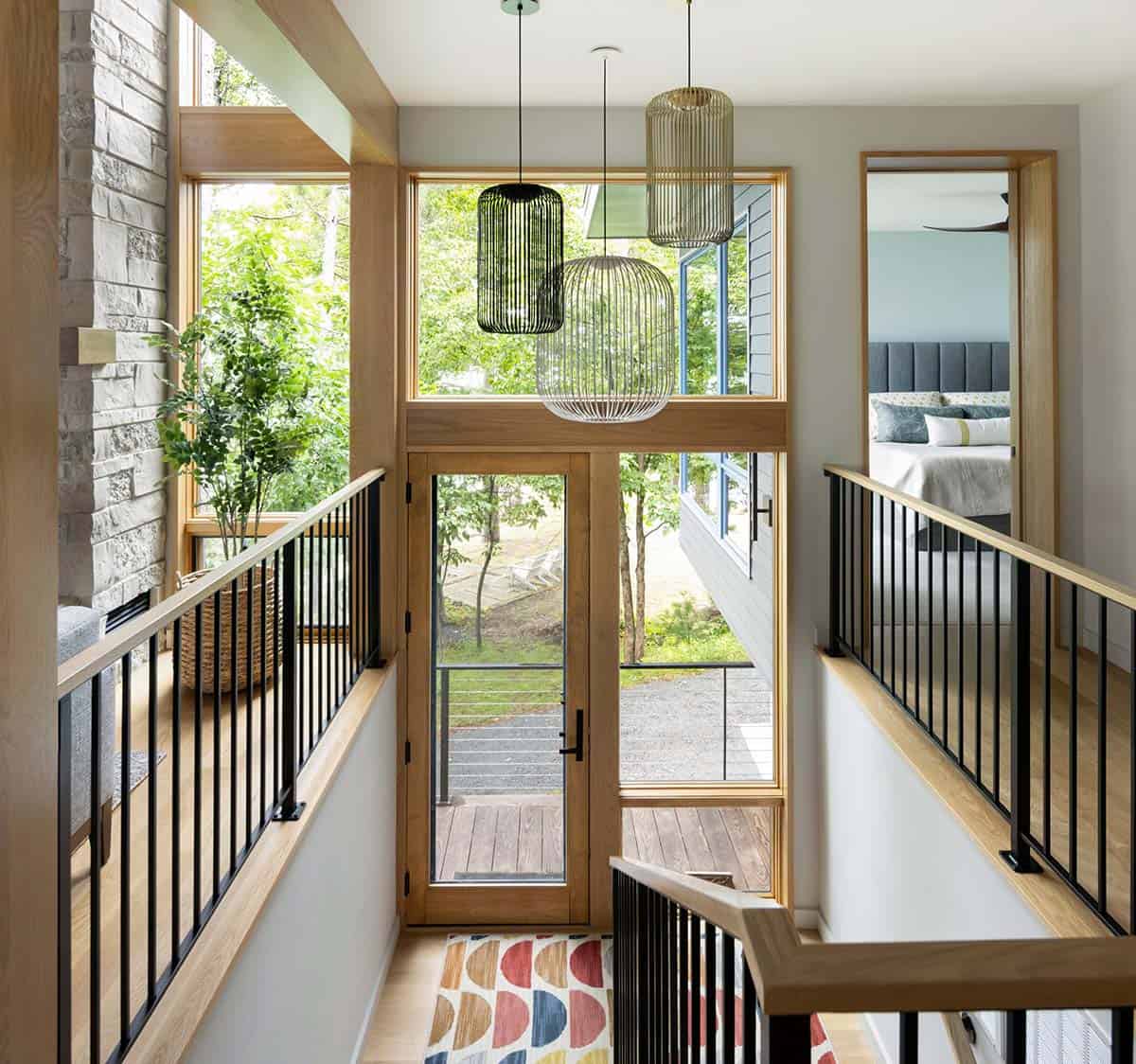 Stairwell landing with wire pendant lights, glass door, and a view of the trees