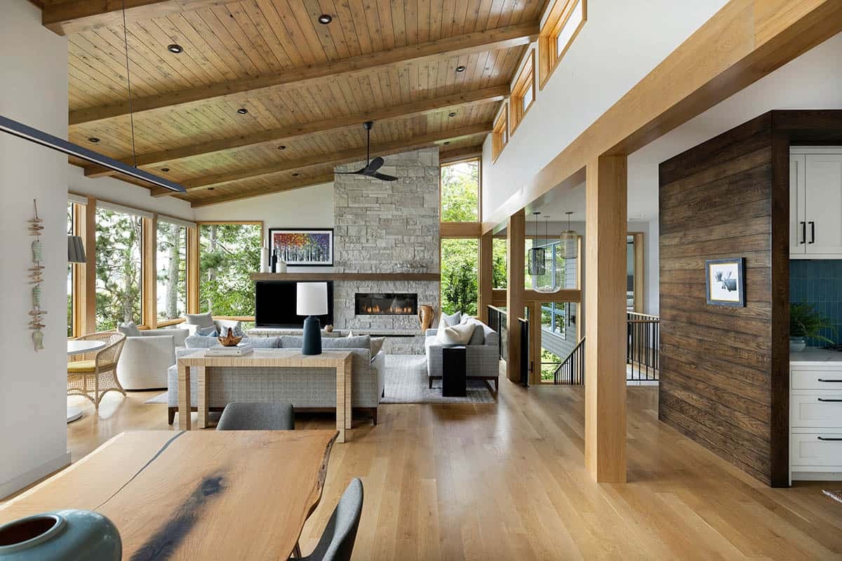 Great room seen from the dining table, with a stone fireplace and timber-beamed ceiling