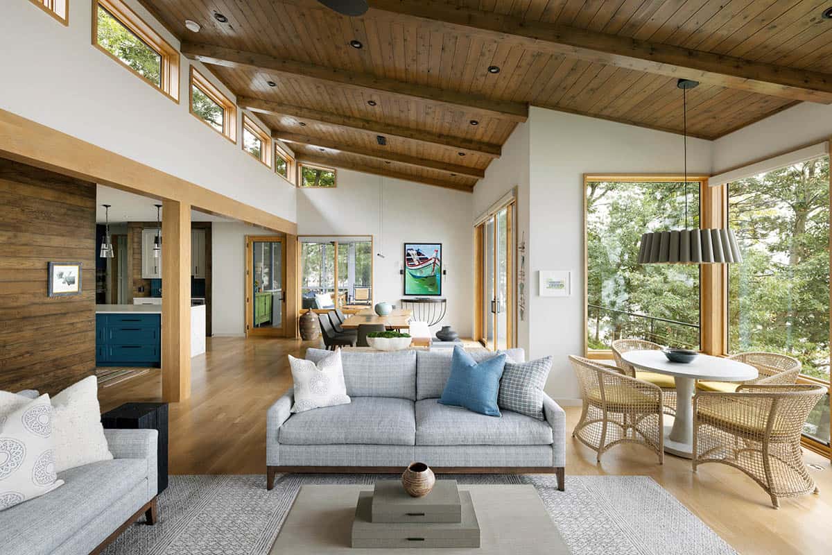 Living room with gray sofa, wicker chairs at a round table, and a wood-beamed vaulted ceiling