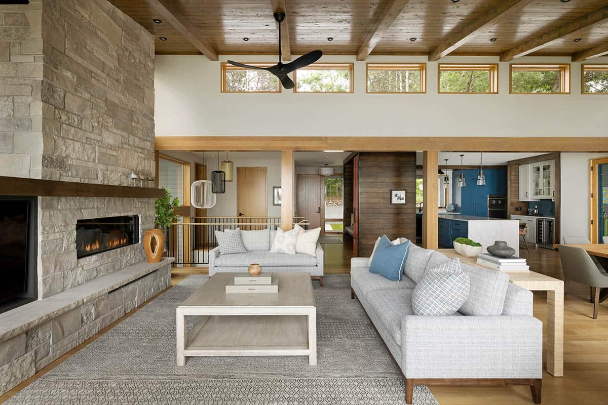 Living room with fireplace, gray sofas, and clerestory windows, with the kitchen behind