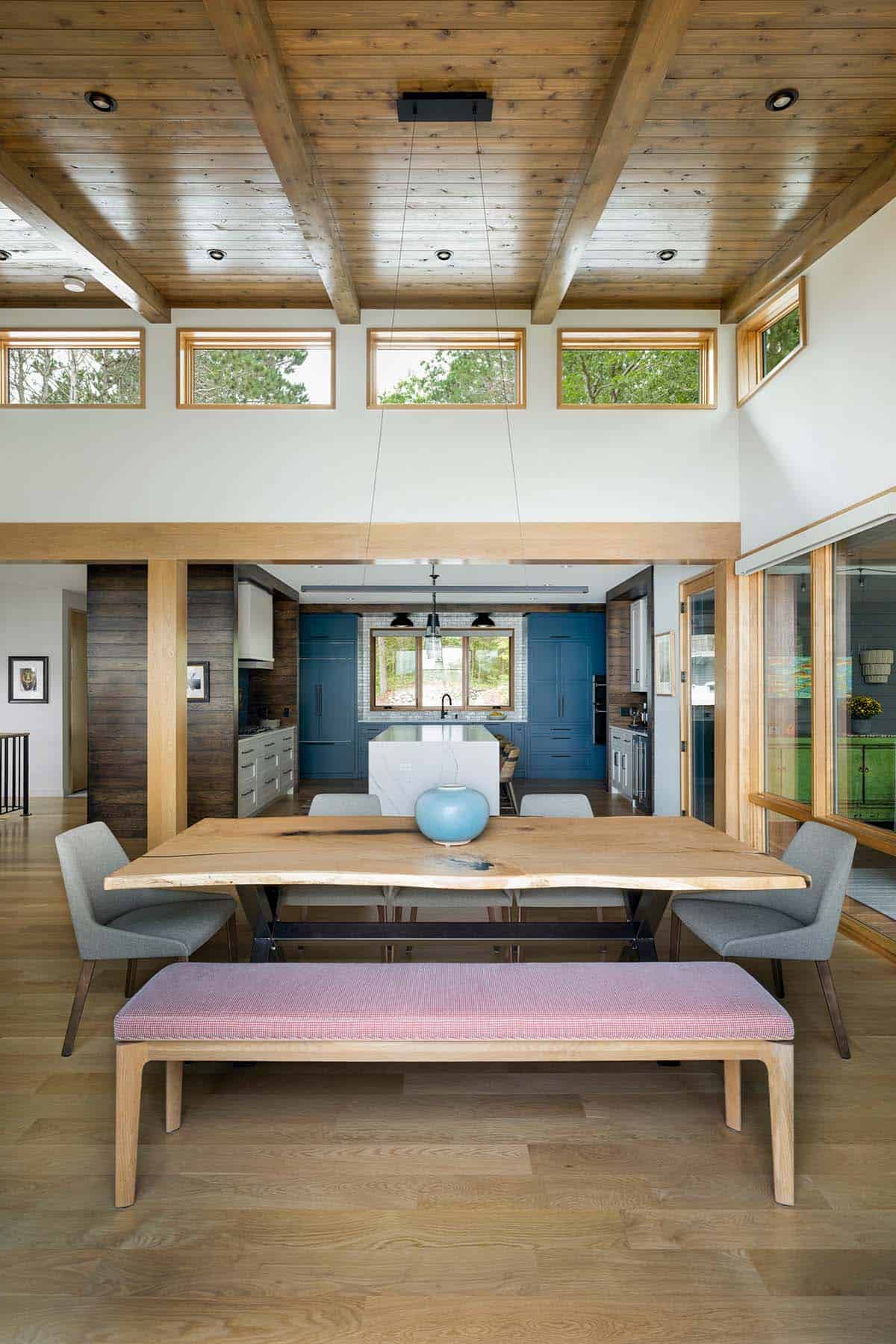 Live-edge dining table with a pink bench, looking through to the blue kitchen