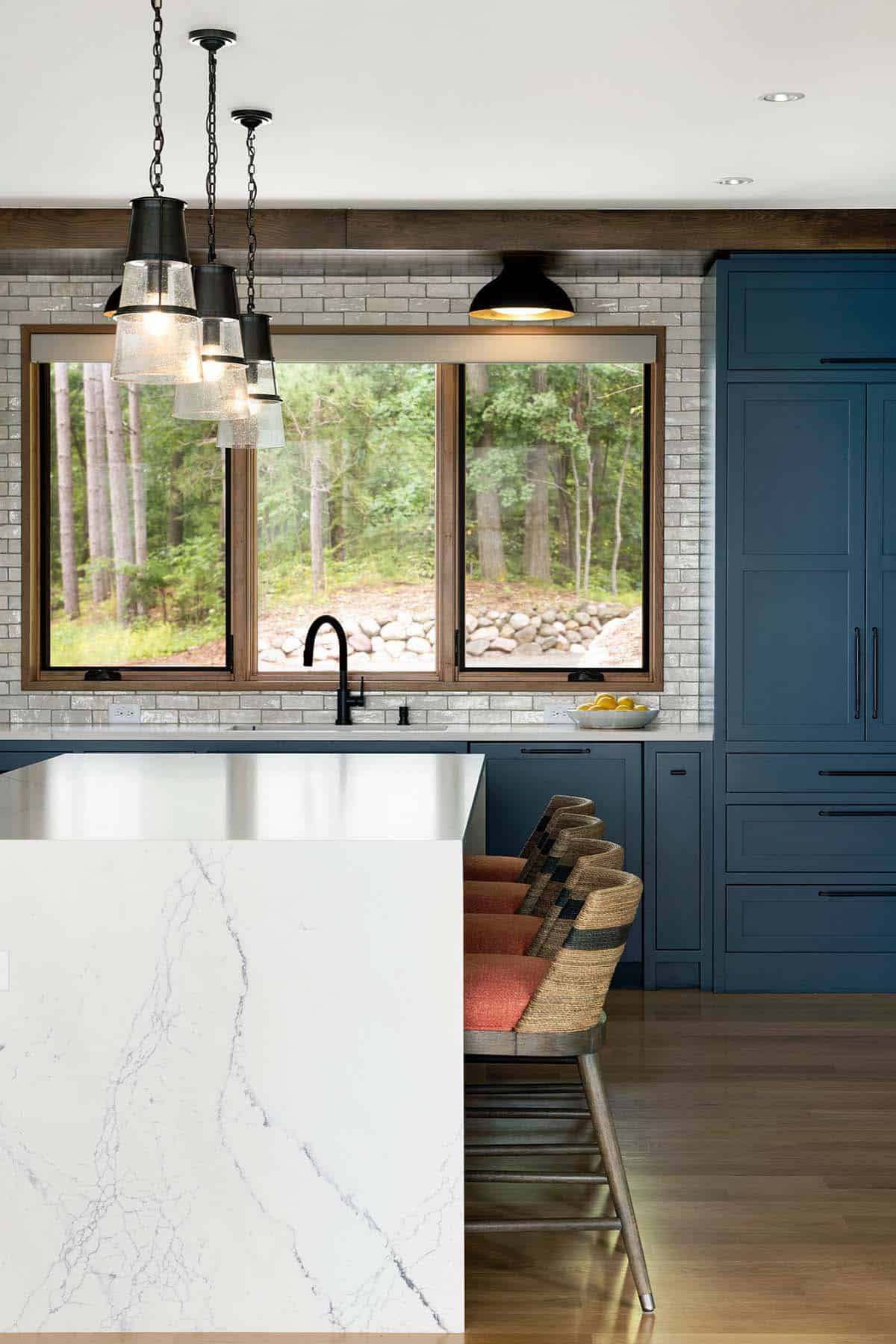 Close-up of the waterfall island, bar stools, and pendants in front of the kitchen window