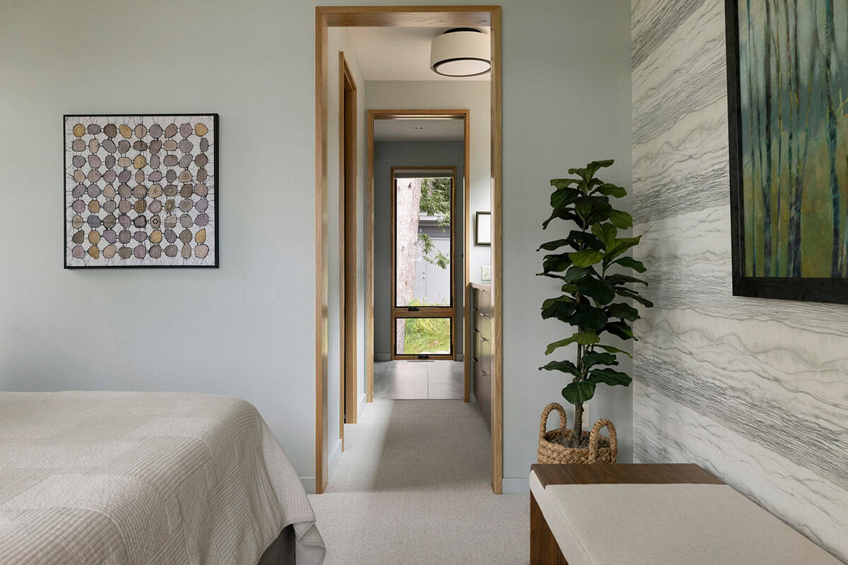 Bedroom hallway view with framed art, a fiddle-leaf fig, and a window at the end