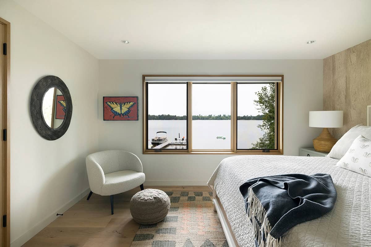 Bedroom with lake views, a dock outside the window, a butterfly painting, and a lounge chair