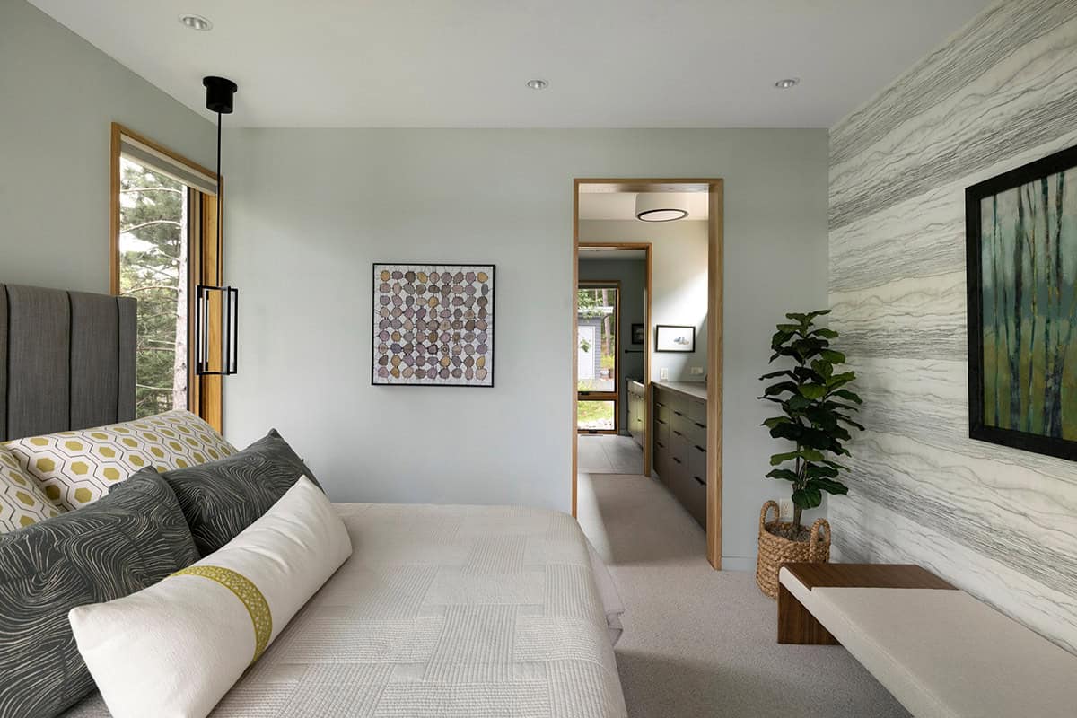 Primary bedroom looking toward the en suite, with a patterned pillow and a leafy plant