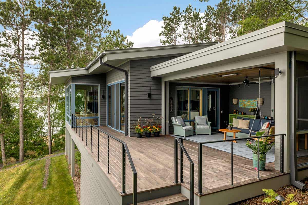 Lakeside deck wrapping from the sunroom to the covered porch, with a porch swing and cable railings