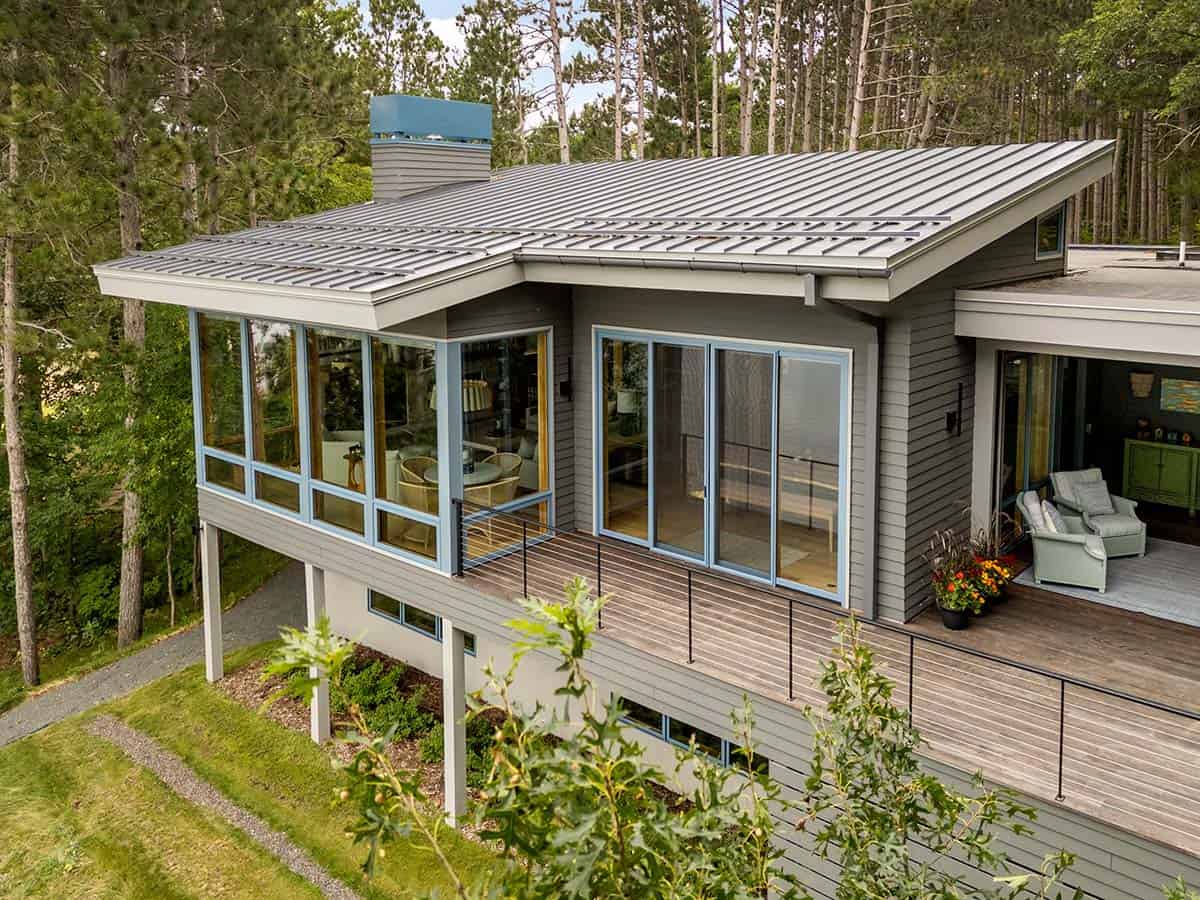 Close aerial view of the sunroom windows, metal roof, and sage chairs on the deck