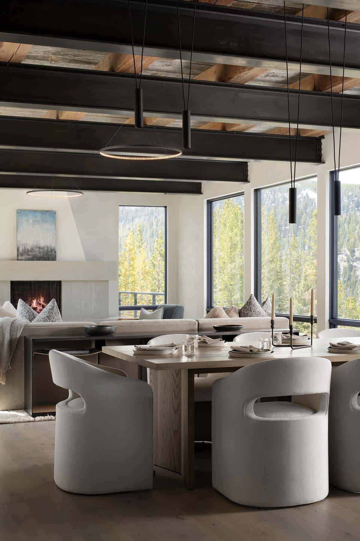 Dining table with white chairs under steel beams and ring pendants