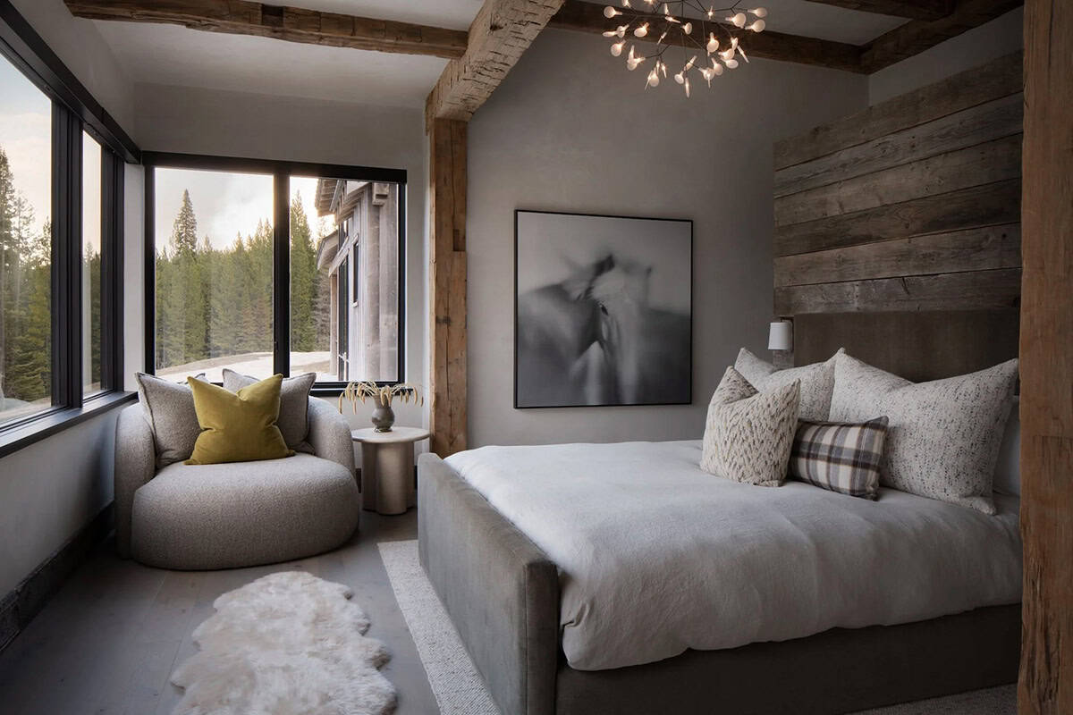 Guest bedroom with a reclaimed wood wall, round chair, and corner windows