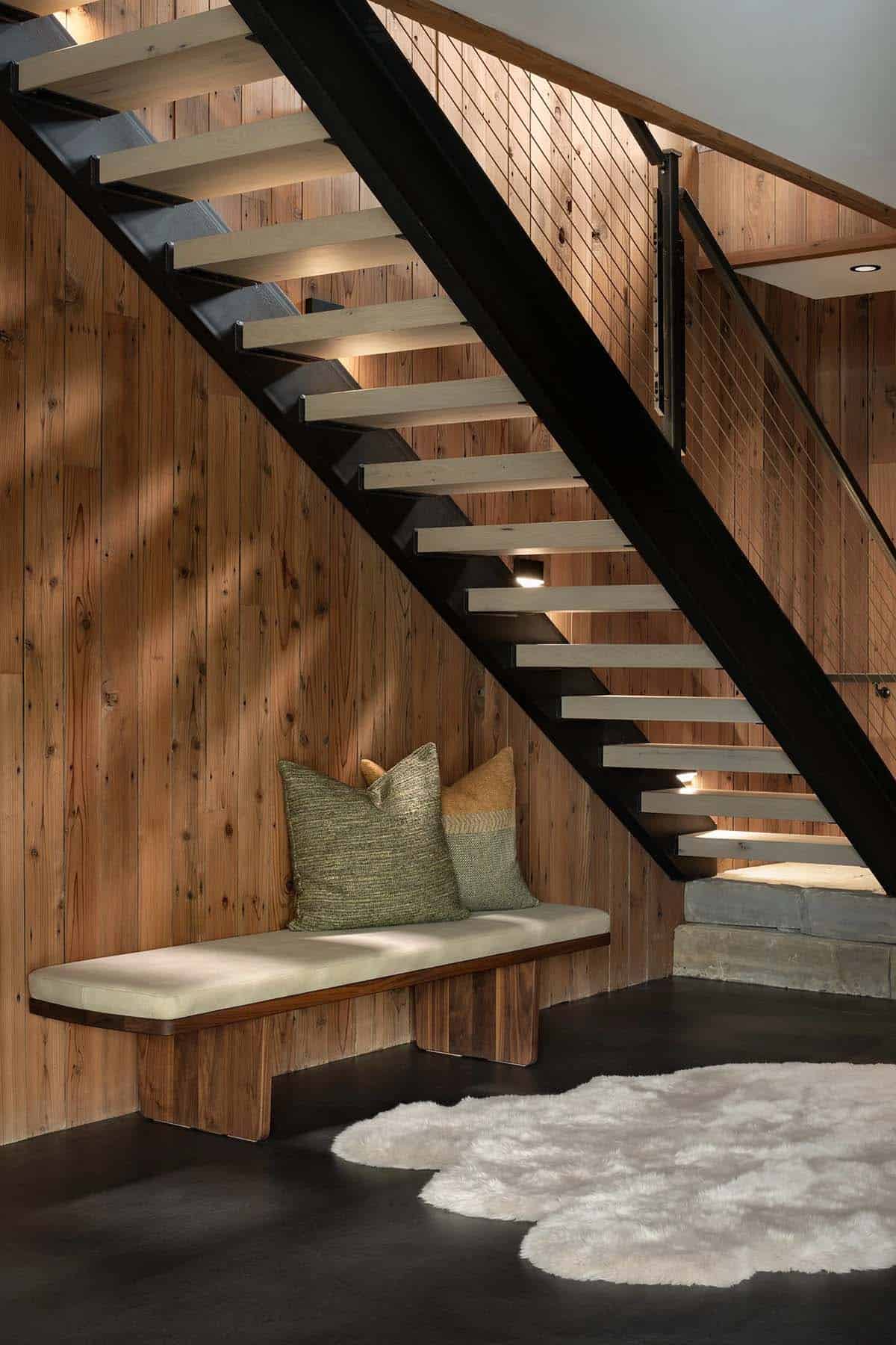 Floating staircase with steel stringers above a cushioned bench
