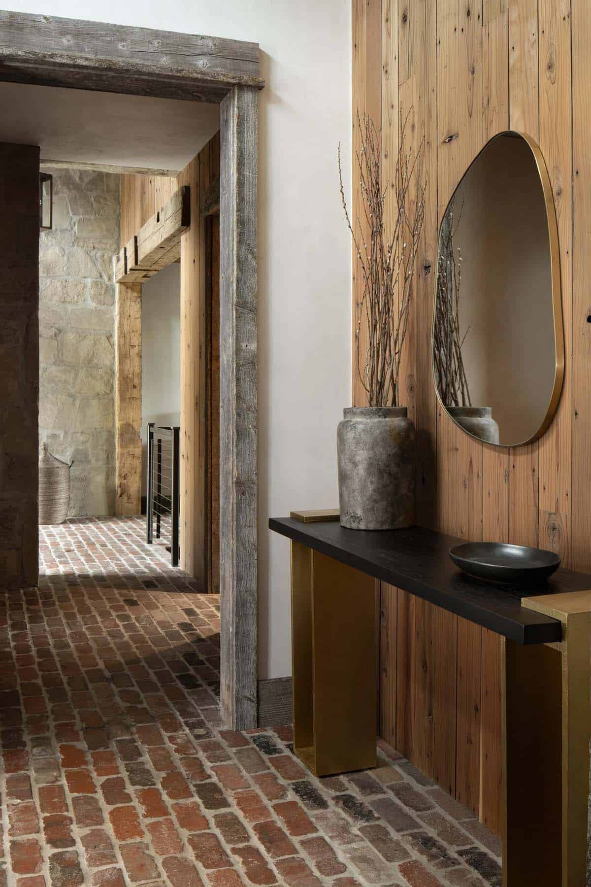 Hallway with brick floor, a brass-framed mirror, and a black console