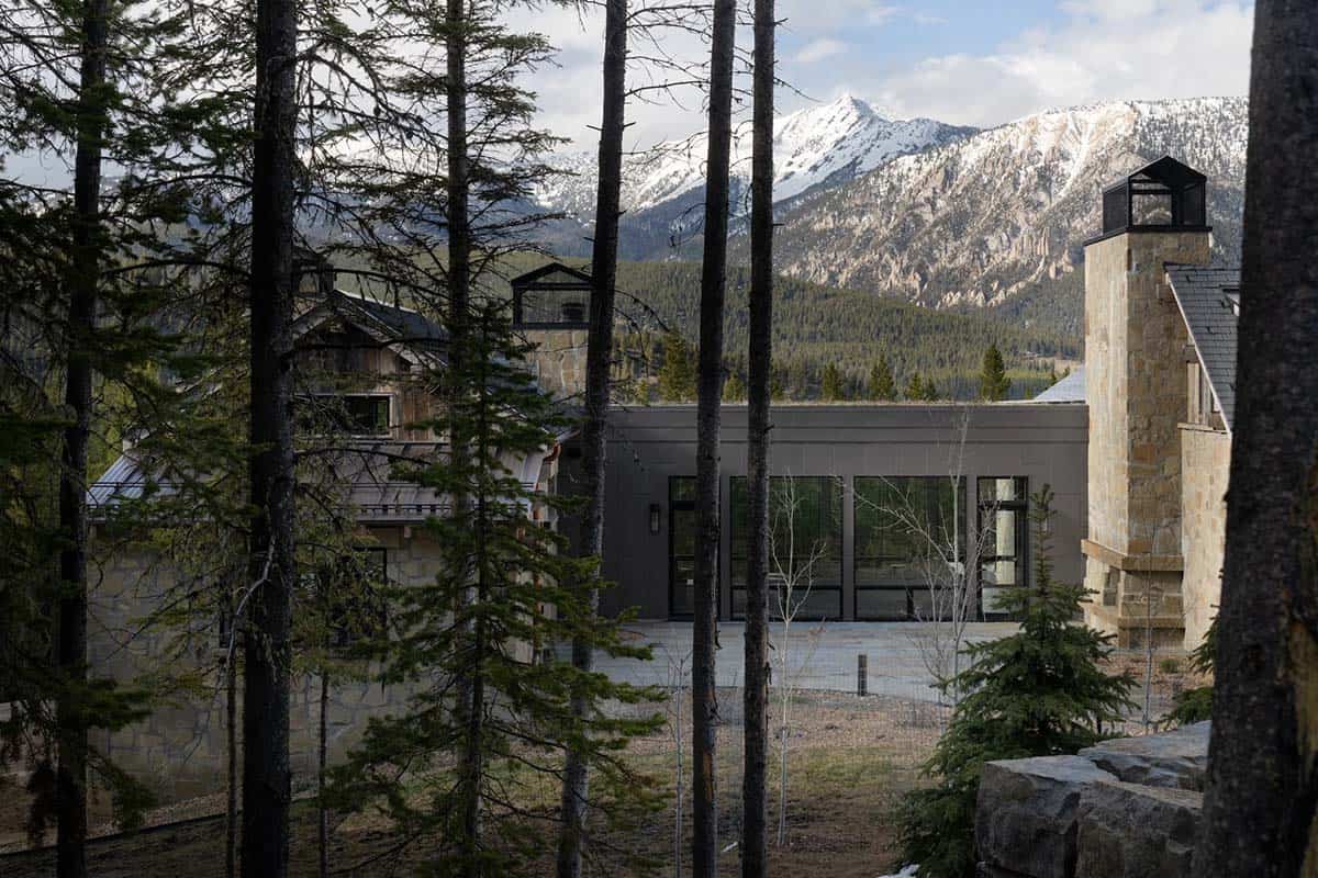 Glass breezeway between stone chimneys with snowcapped peaks behind