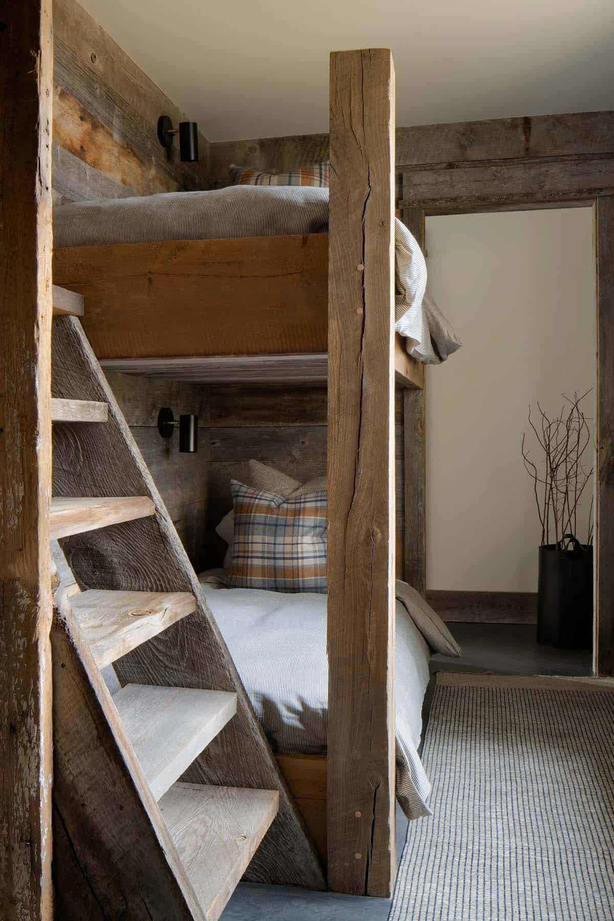 Bunk beds built from reclaimed wood with a ladder and plaid pillows