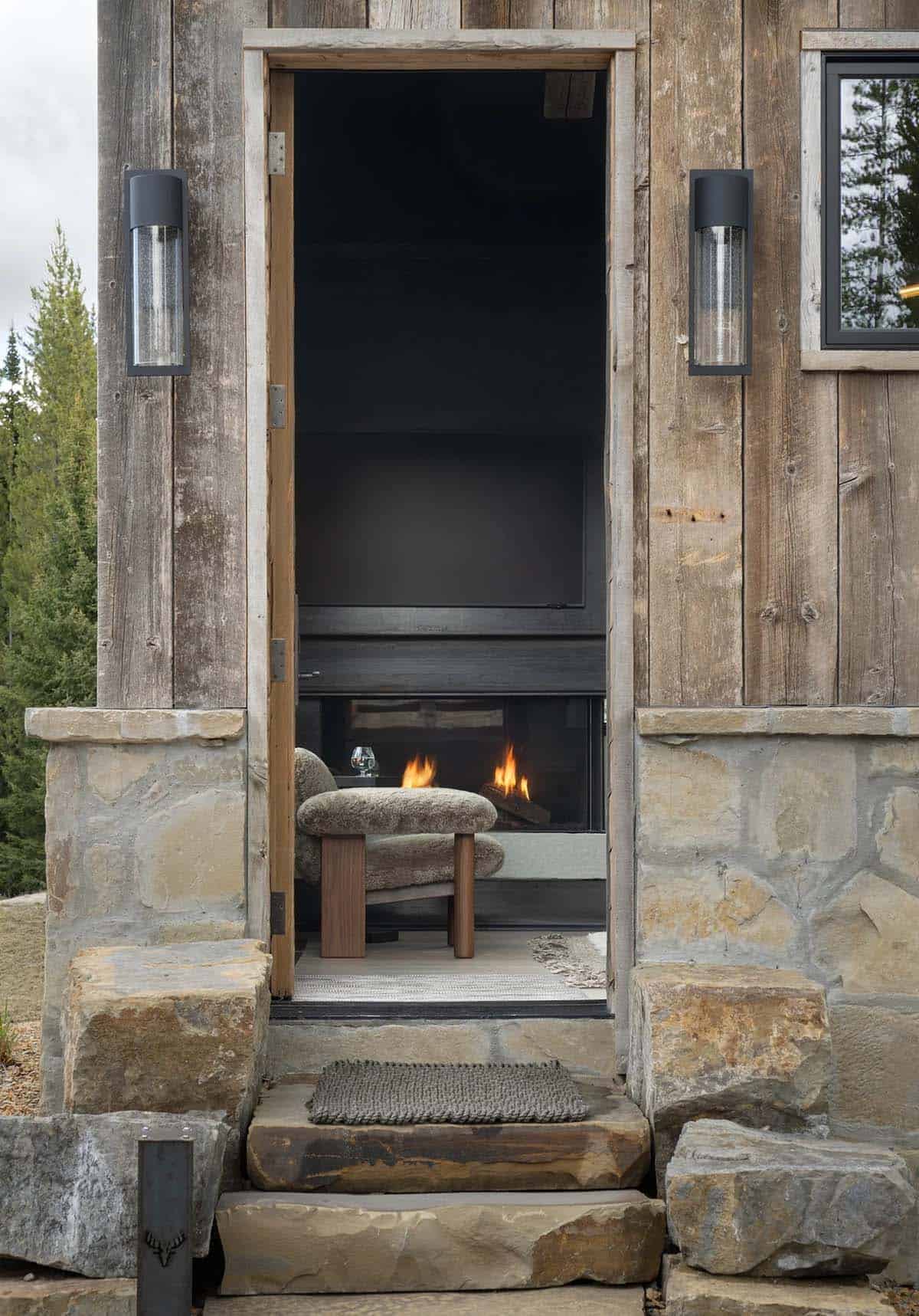 Open doorway in a wood and stone wall showing a chair by a fireplace